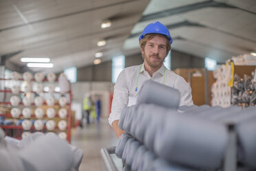 Portrait of smiling man wearing hard hat in factory - ZEF15127