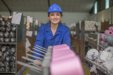 Porträt einer lächelnden Frau mit Schutzhelm in einer Fabrik - ZEF15129