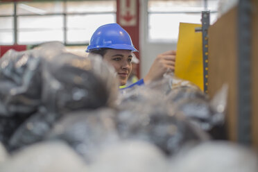 Woman wearing hard hat checking document in factory - ZEF15130