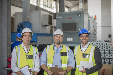 Portrait of smiling businessman with staff in factory - ZEF15133