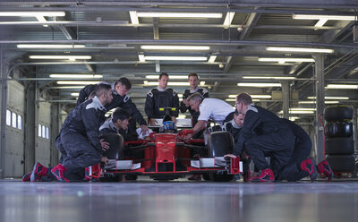 Rennwagenteam bei der Arbeit am Rennwagen in der Garage - CAIF06362