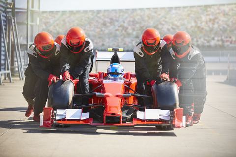 Boxencrew schiebt Formel-1-Rennwagen aus der Boxengasse, lizenzfreies Stockfoto