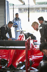 Formel-1-Fahrer beobachtet Boxencrew bei der Arbeit am Rennwagen in der Reparaturwerkstatt - CAIF06395