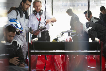 Manager und Formel-1-Fahrer beobachten die Arbeit der Boxencrew am Rennwagen in der Reparaturwerkstatt - CAIF06396