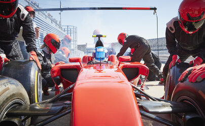 Pit crew replacing tires on formula one race car in pit lane - CAIF06443