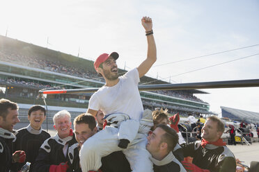 Formel-1-Rennteam trägt jubelnden Fahrer auf den Schultern und feiert den Sieg auf der Sportstrecke - CAIF06470