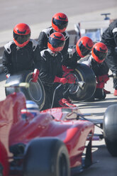 Pit crew with tires ready for nearing formula one race car in pit lane - CAIF06498