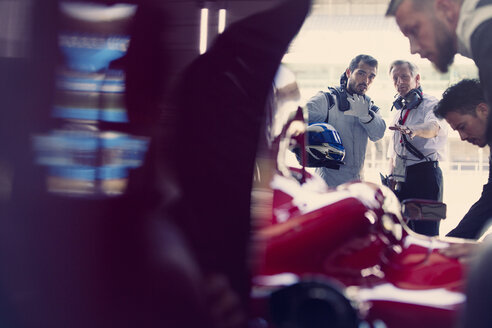 Manager und Formel-1-Rennfahrer unterhalten sich in der Reparaturwerkstatt - CAIF06536