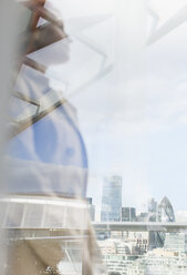 Nachdenkliche Geschäftsfrau mit Blick auf die Stadt von einem städtischen Balkon aus, London, UK - CAIF06559