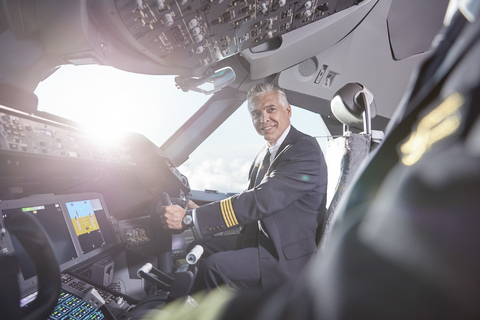 Lächelnde Piloten, die sich im Cockpit eines Flugzeugs unterhalten, lizenzfreies Stockfoto