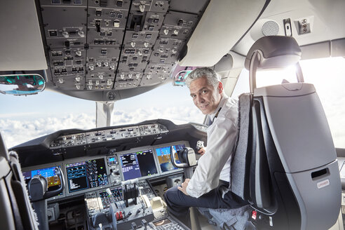 Porträt selbstbewusster männlicher Pilot im Cockpit eines Flugzeugs - CAIF06565