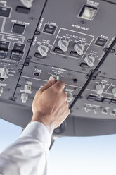 Pilot adjusting control instruments in airplane cockpit - CAIF06568