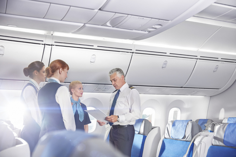 Pilot and flight attendants talking, preparing on airplane stock photo