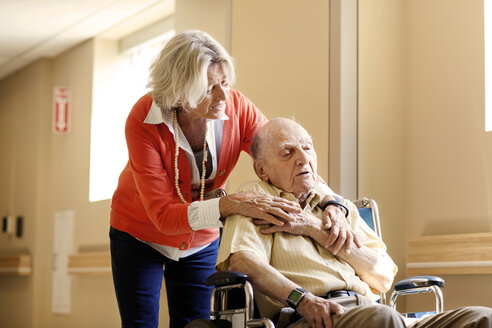 Besorgte Frau mit älterem Mann im Rollstuhl im Krankenhaus - CAVF01116