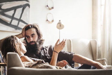 Couple talking while sitting on sofa at home - CAVF01156