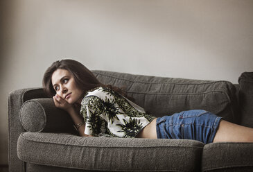 Seitenansicht einer Frau, die sich zu Hause auf dem Sofa entspannt - CAVF01173