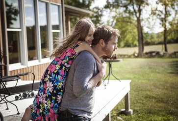 Side view of man piggybacking girl in lawn - CAVF01193