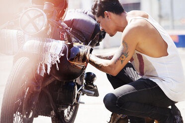 Seitenansicht eines Mannes mit Blick auf einen Motorradmotor - CAVF01224