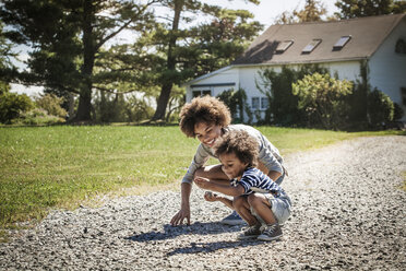 Happy siblings collecting stones at backyard - CAVF01236