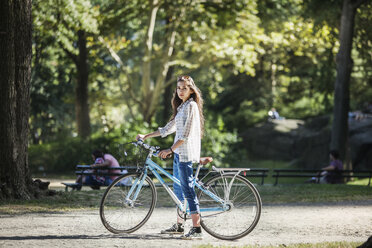 Portrait of woman with bicycle standing on footpath - CAVF01250