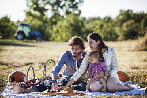 Familie isst Früchte beim Picknick an einem sonnigen Tag, lizenzfreies Stockfoto