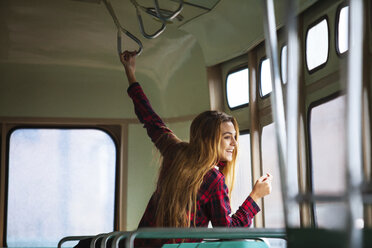 Happy woman looking through tram window - CAVF01300