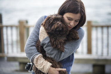 Frau umarmt Hund, während sie am Hudson River steht - CAVF01348