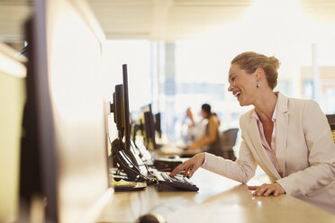 Lachende Geschäftsfrau bei der Arbeit am Computer im Büro - CAIF06606