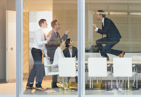 Exuberant businessman gesturing with fists on top of conference table stock photo