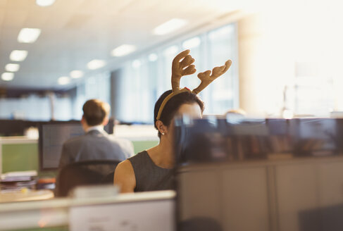 Businesswoman wearing antler headband in office - CAIF06638