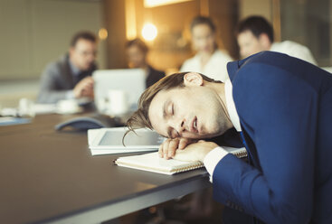 Businessman sleeping in conference room meeting - CAIF06640