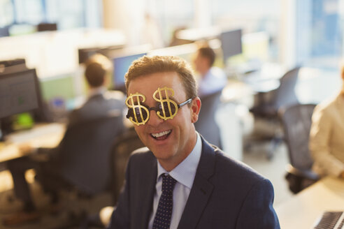 Portrait lächelnder Geschäftsmann mit Dollarzeichen-Sonnenbrille im Büro - CAIF06641