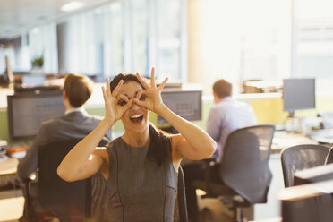 Porträt einer verspielten Geschäftsfrau, die vorgibt, im Büro eine Brille zu tragen - CAIF06643