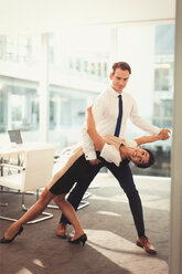 Portrait of businessman and businesswoman dancing tango in conference room - CAIF06650