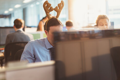 Businessman wearing antler headband in office - CAIF06660