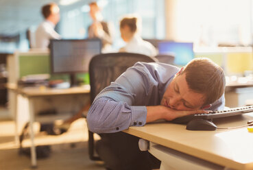 Geschäftsmann schläft auf dem Schreibtisch im Büro - CAIF06664