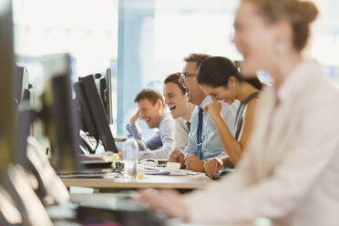 Geschäftsleute lachen am Schreibtisch im Büro - CAIF06673