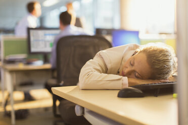 Geschäftsfrau schläft auf dem Schreibtisch im Büro - CAIF06680