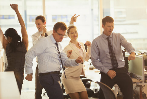 Enthusiastische Geschäftsleute feiern und tanzen im Büro - CAIF06683