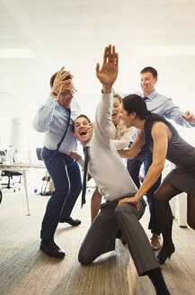 Exuberant business people celebrating and dancing in office - CAIF06685