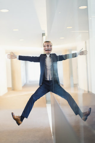 Symmetrical reflection portrait of businessman with arms and legs outstretched in office corridor stock photo