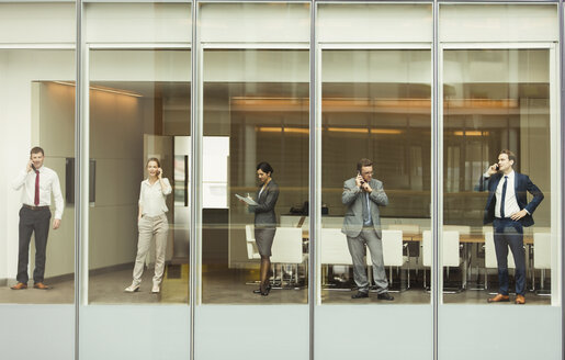 Geschäftsleute, die am Fenster des Konferenzraums mit Handys telefonieren und Papierkram durchgehen - CAIF06731