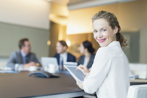 Portrait smiling businesswoman using digital tablet in conference room meeting stock photo