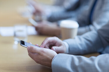 Nahaufnahme eines Geschäftsmannes, der in einer Besprechung ein Mobiltelefon benutzt - CAIF06742