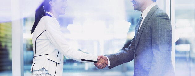 Businessman and businesswoman handshaking in office - CAIF06762