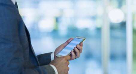 Businessman using cell phone in office - CAIF06763