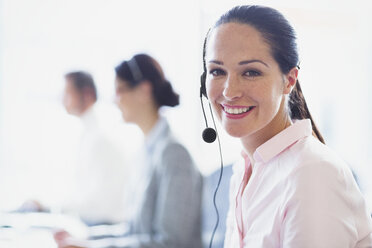 Portrait of smiling businesswoman talking on the phone with headset - CAIF06770