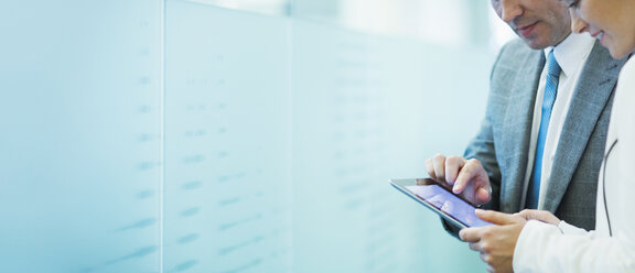 Geschäftsmann und Geschäftsfrau verwenden digitale Tablet im Bürokorridor - CAIF06771