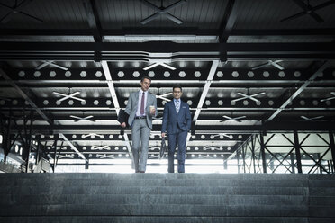 Corporate businessmen with coffee descending modern stairs - CAIF06777