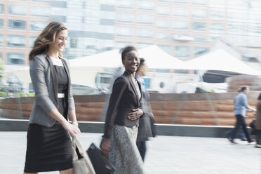 Portrait smiling corporate businesswoman walking outdoors - CAIF06790